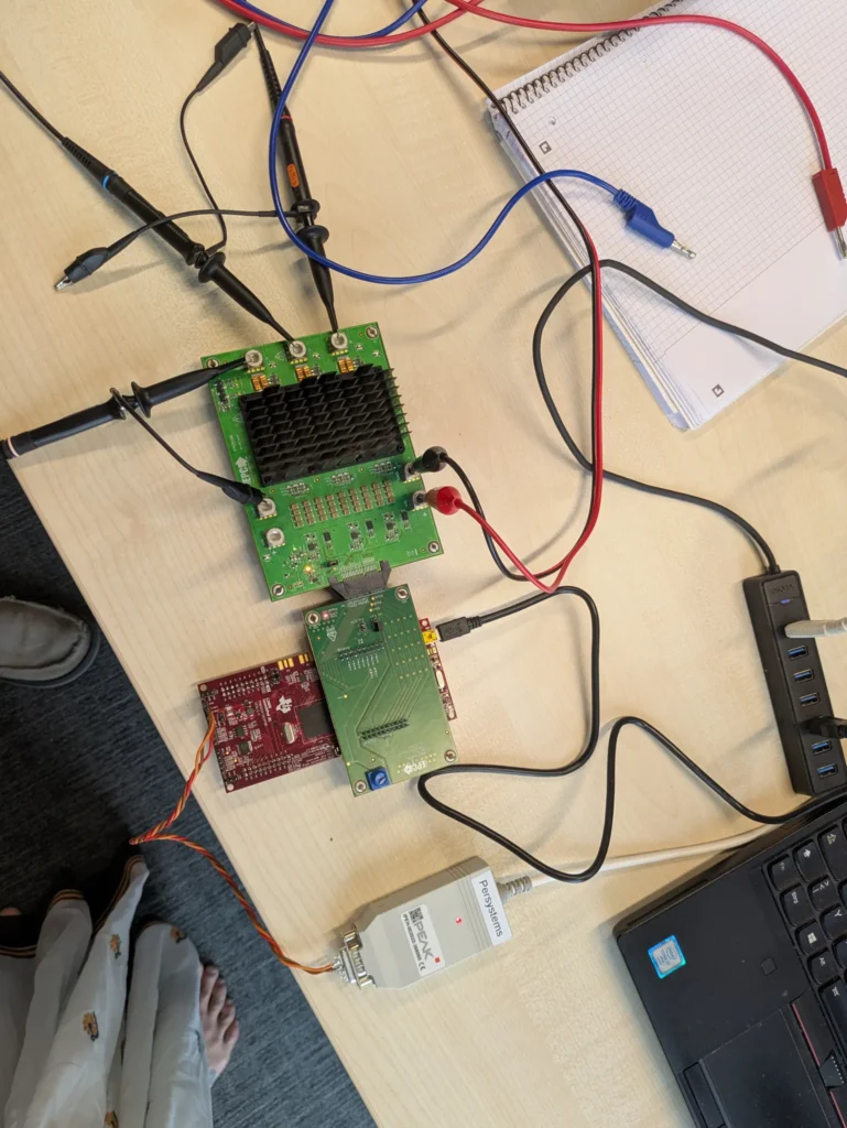 Inverter-Platine am Prüfplatz mit Oszilloskop-Tastköpfen, Entwicklungsboard und Notizen