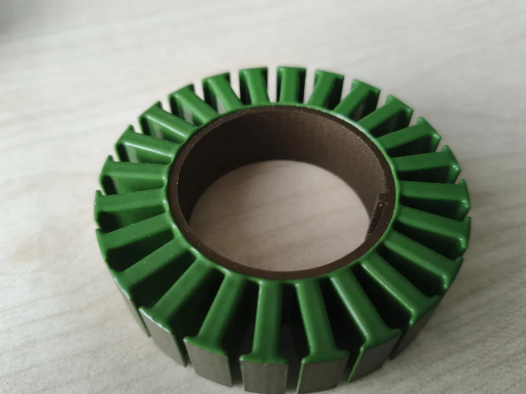 Stator lamination stack of an outrunner motor with green insulation layer on a desk