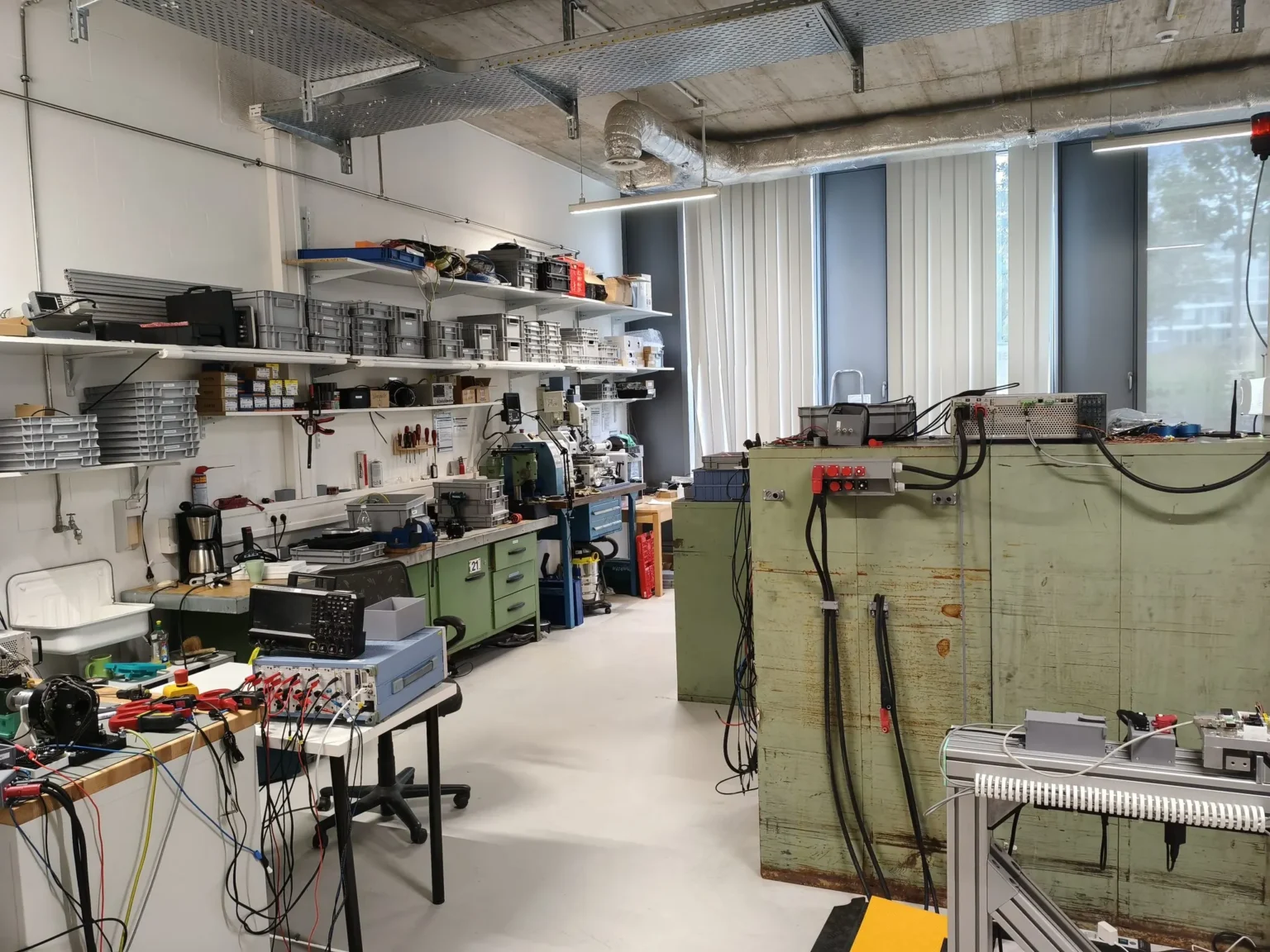 Persystems workshop in Regensburg: workbenches, shelves with material, test setups